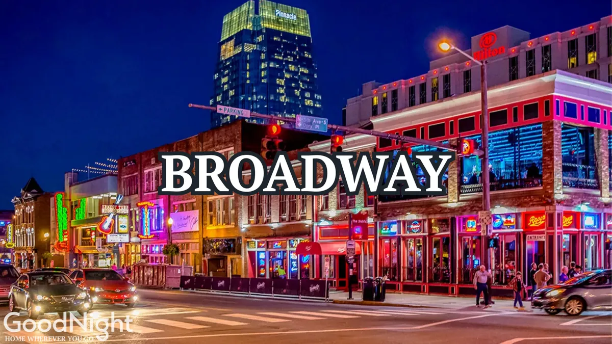 A bustling city street illuminated by neon signs, with people walking, cars in motion, and venues offering entertainment, dining, and nightlife. The scene radiates energy and the excitement of Nashville after dark.
