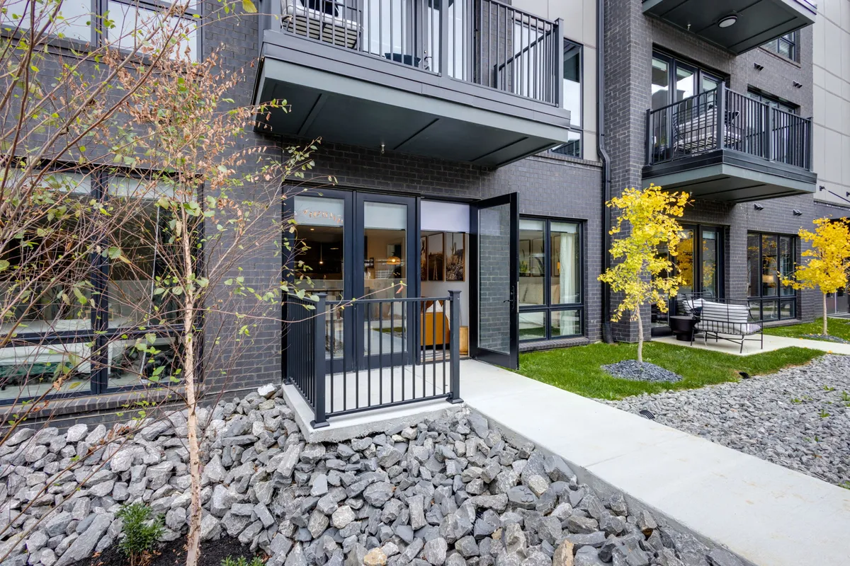 The image showcases the welcoming exterior entrance, balcony, decorative trees, and rock landscaping of the home. It hints at outdoor relaxation areas perfect for barbecues, poolside fun, and evening gatherings after a day of exploring Nashville.